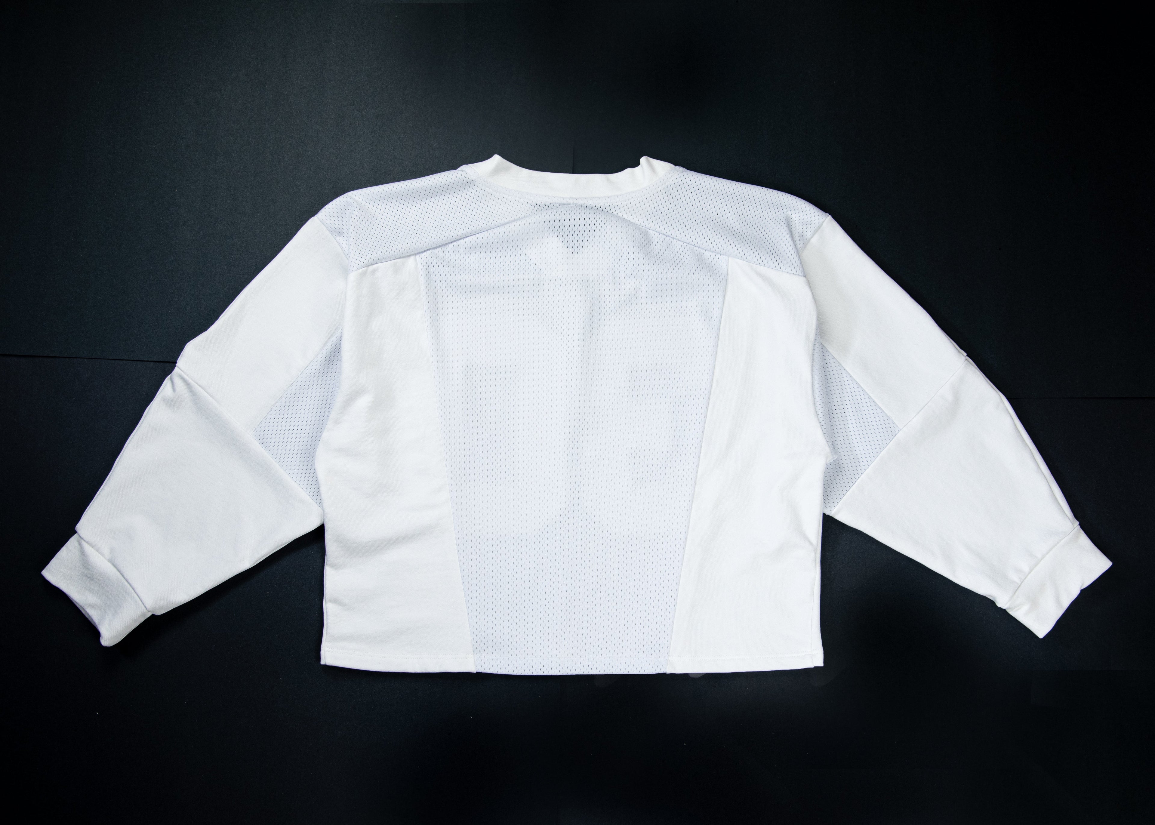 A white long-sleeve athletic jersey shown from the back, laid flat on a dark black background. The back features a large, tonal number '16' printed across the center.
