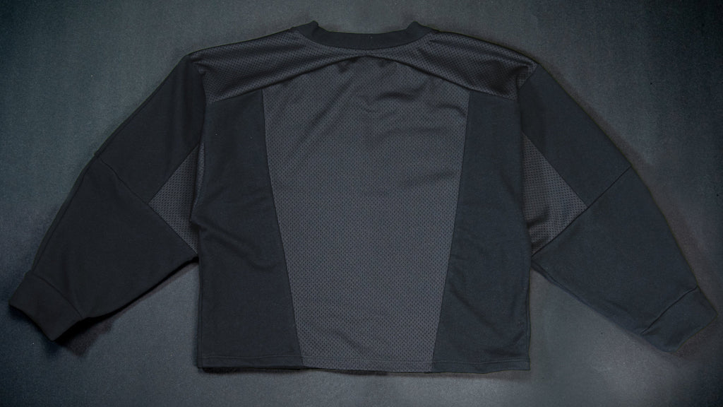 A black long-sleeve sweatshirt shown from the back, laid flat on a dark textured background.