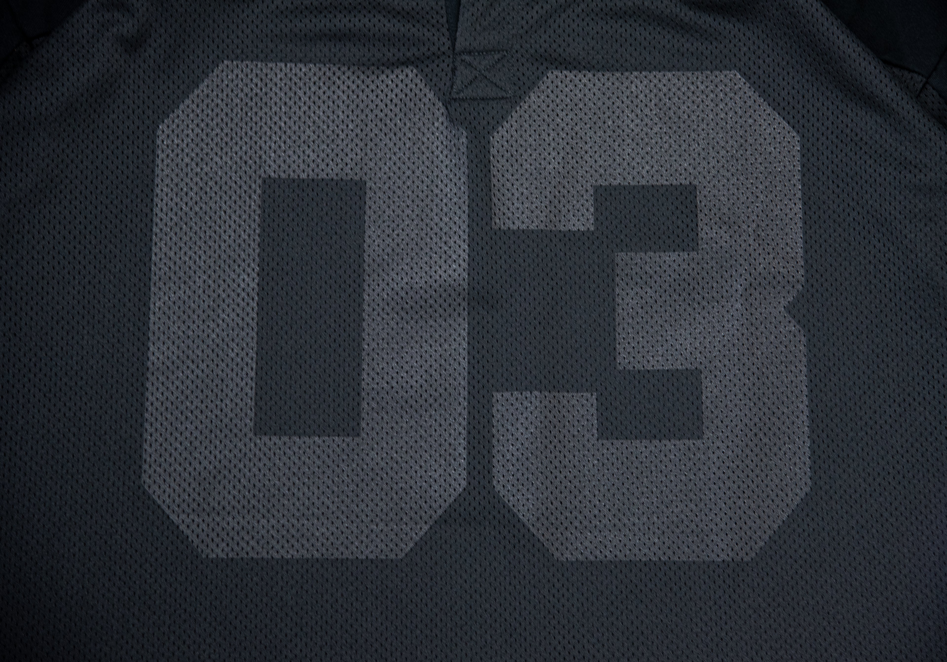 Close-up of a black athletic jersey showing the back with a large light gray number 03 printed on it.