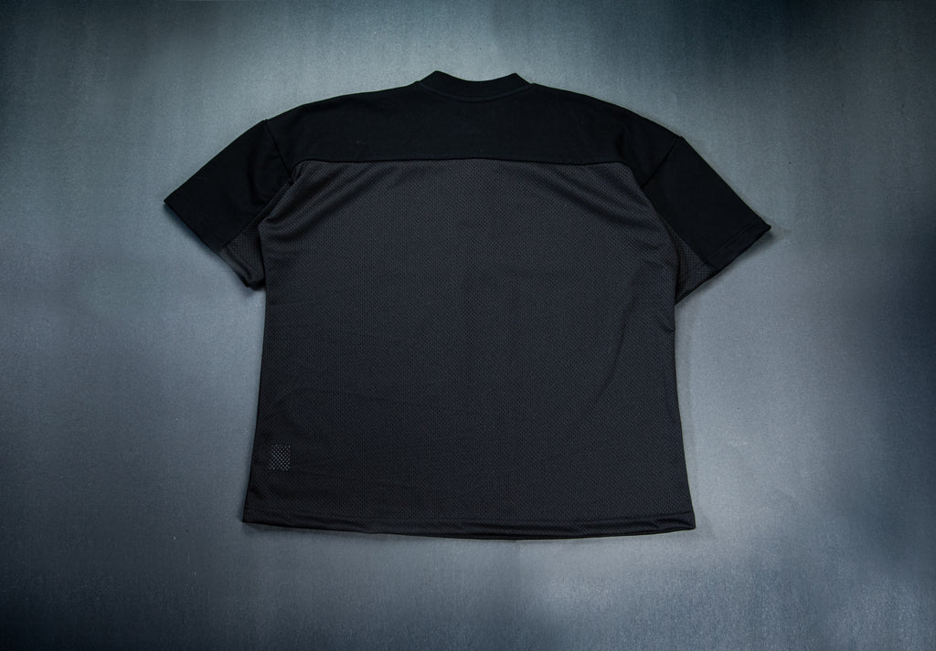 A black on black short-sleeve athletic t-shirt with a color-blocked design featuring a solid black yoke and shoulders, laid flat on a dark gray textured background.
